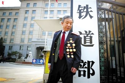 3月14日，铁道部大门口，一位胸前挂着多枚勋章的铁道部老职工与铁道部牌子合影。